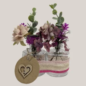 imagen de Envases de vidrio con flores artificiales. Tono rosa y morado.