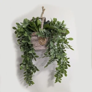 imagen de una cesta colgante rellena de flores artificiales. Tono verde y marrón